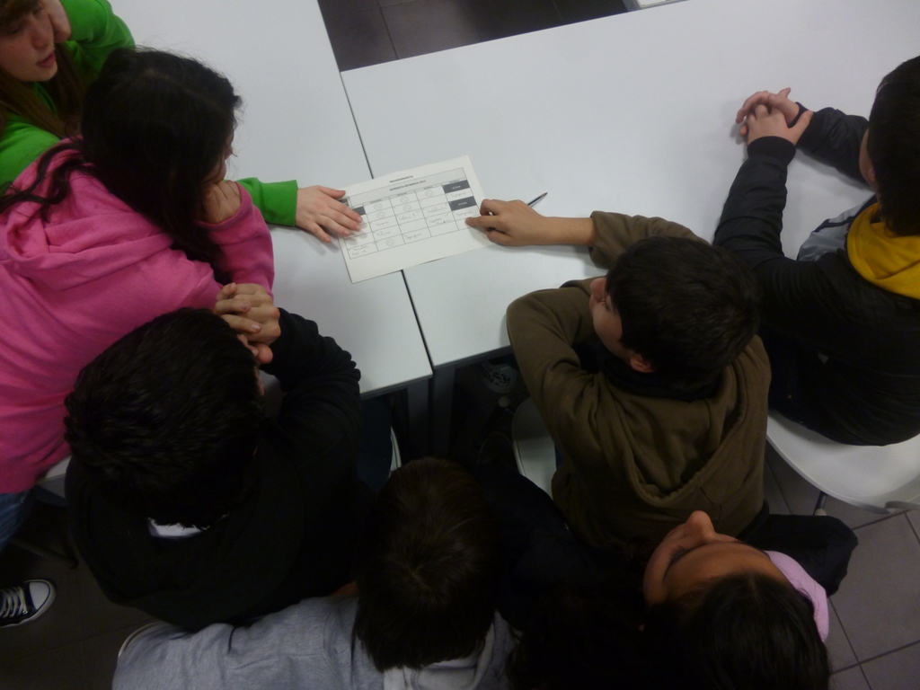 Grupo de nios sentados frente a una mesa miran un papel que muestra un horario