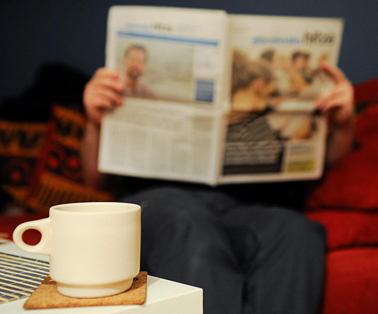 Una persona lee el peridico tras una taza de caf