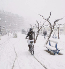 Una persona atraviesa la calle nevada en una bicicleta